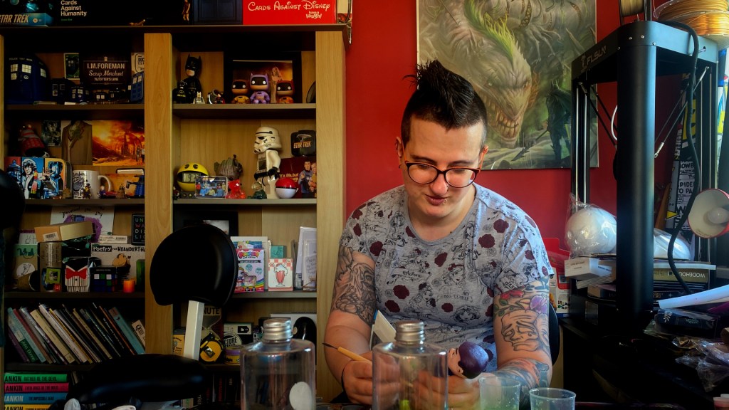 A woman sat at her desk making a sculpture.