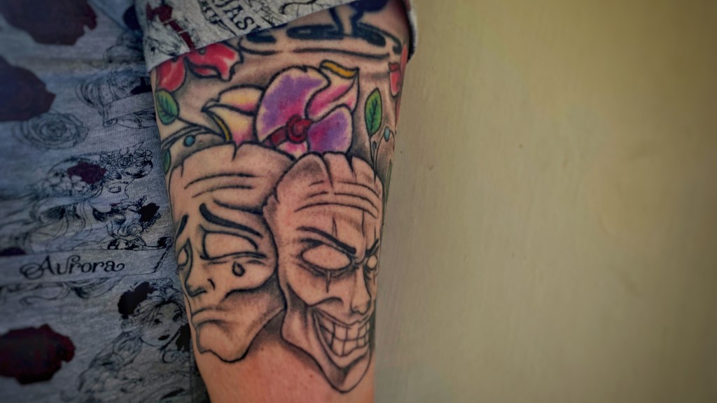 Tattoos of theatrical faces, the sad and the happy. 