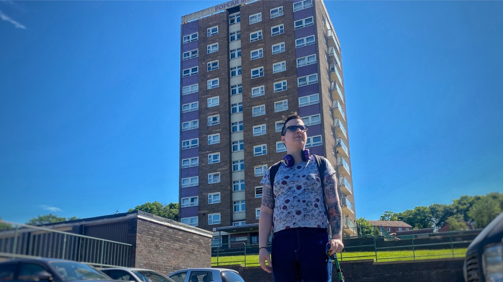 A woman stood in front of the tower block she lives in.