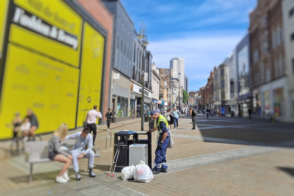 a man empty's a bin next to the now empty Topshop