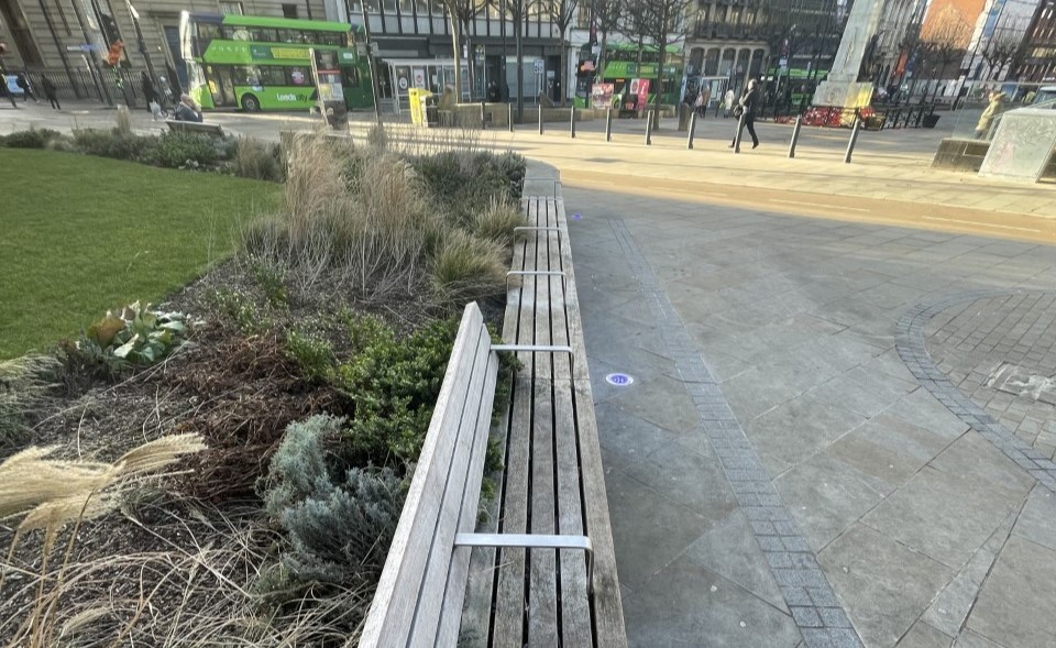 A bench in Leeds with silver handles breaking the bench up