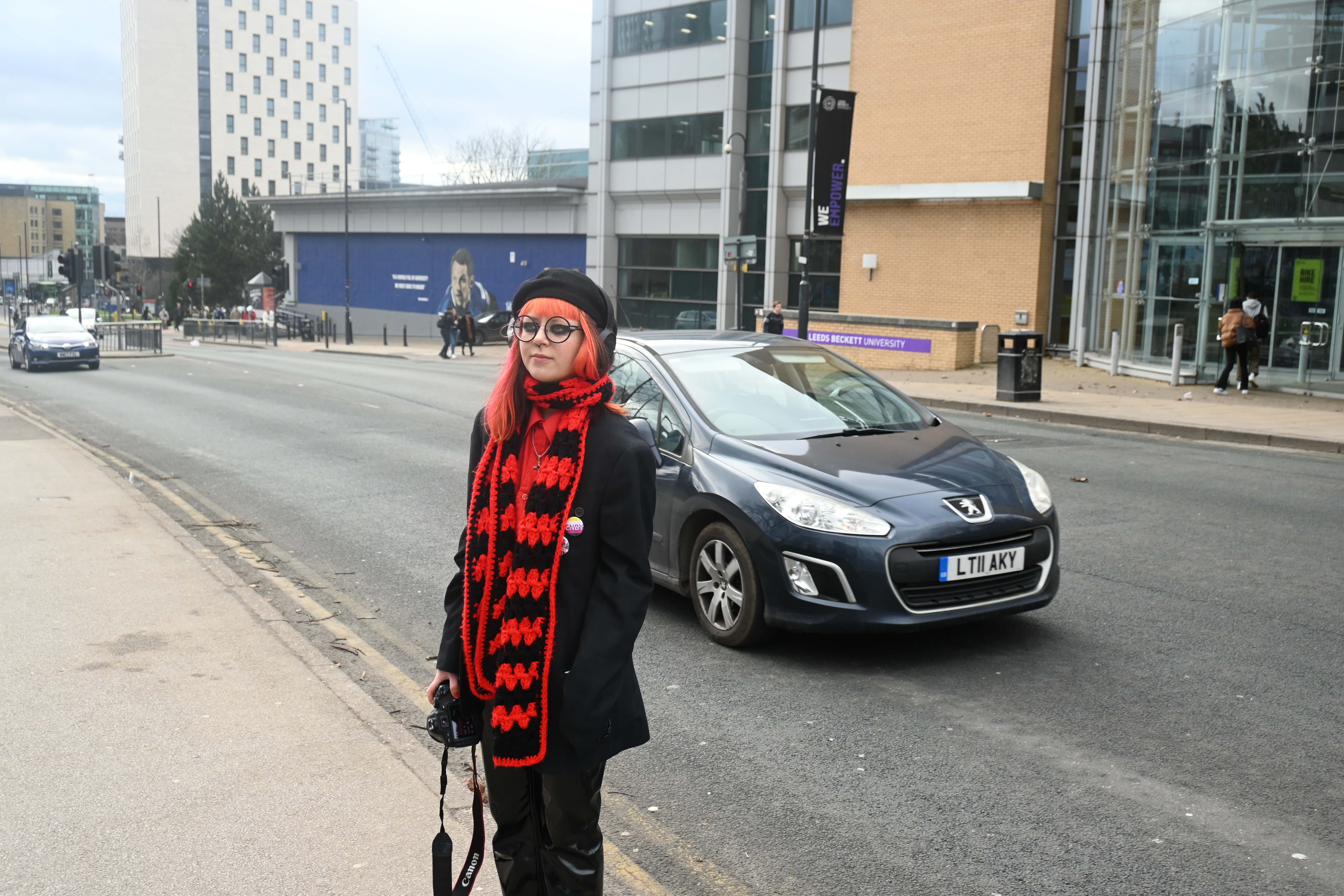 person standing in road with car driving behind them