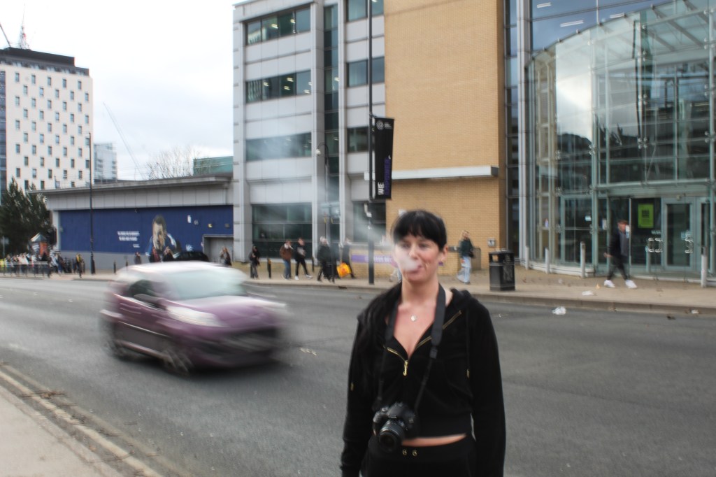 Rai stood on side of the road as a car drives past