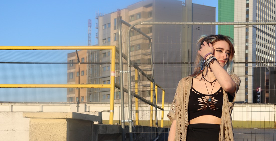 An image of a female walking down a hill of a parking lot moving her hair from her face.