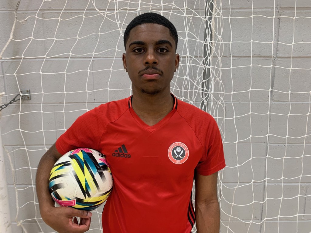 A close up shot of Carlos Nunes whilst he is holding a futsal ball underneath his right arm.