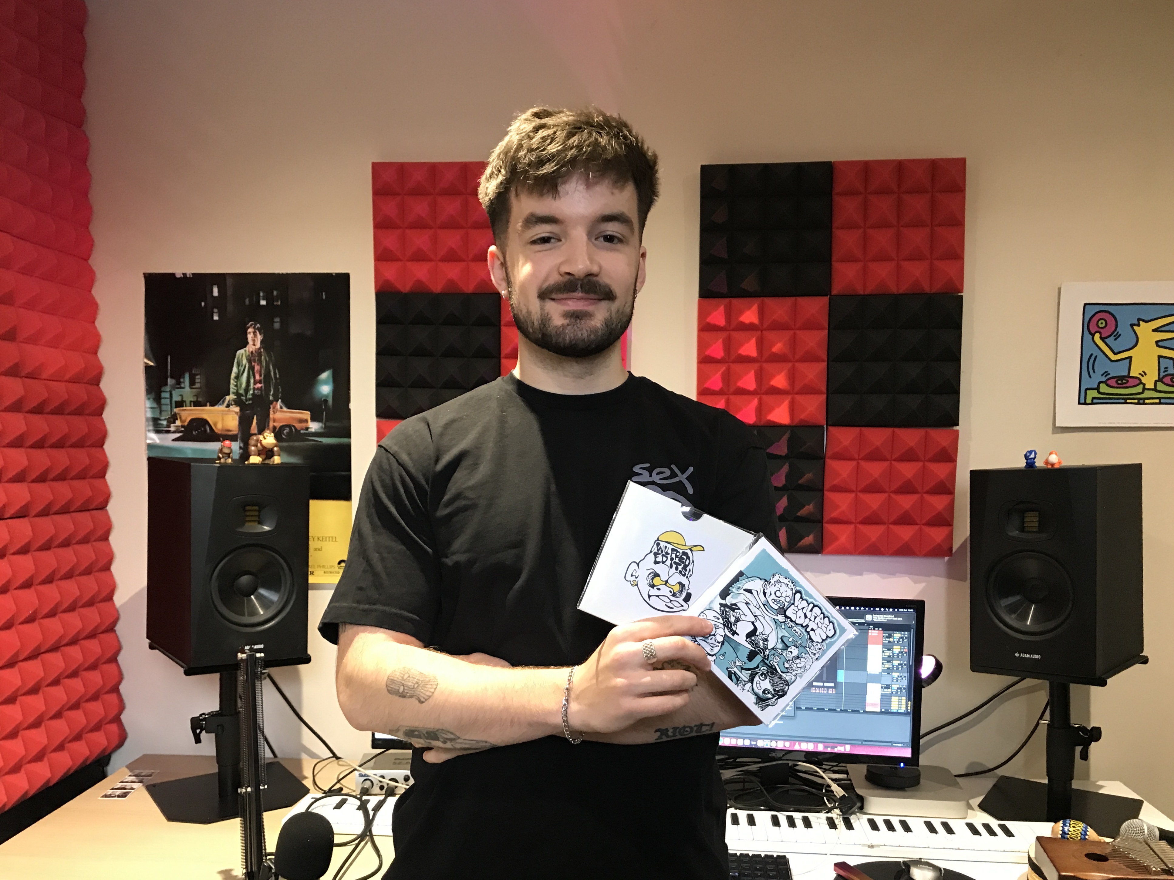 A man in a recording studio holding two albums