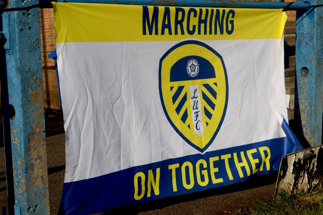 A flag of the Leeds United badge with marching on together written on it.