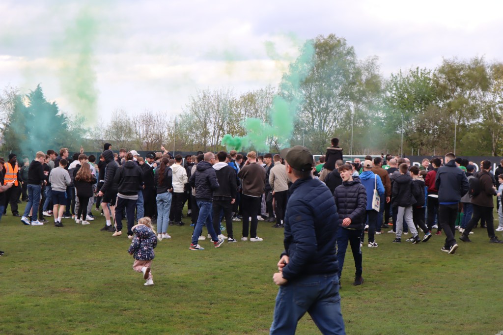 Farsley Celtic supporters celebrate on the pitch after avoiding relegation.