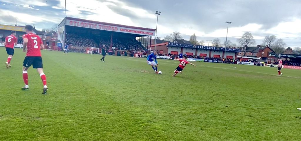 Altrincham's number 26 lunges towards his opponent.