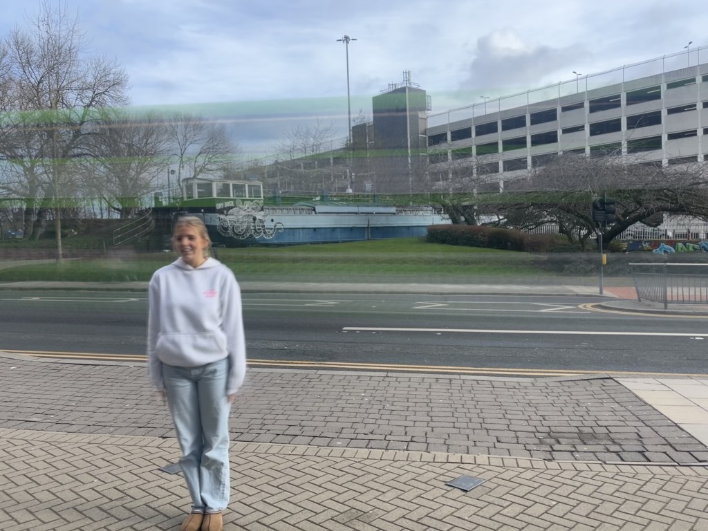 A girl stands infrotn of a road in Leeds as a bus drives past