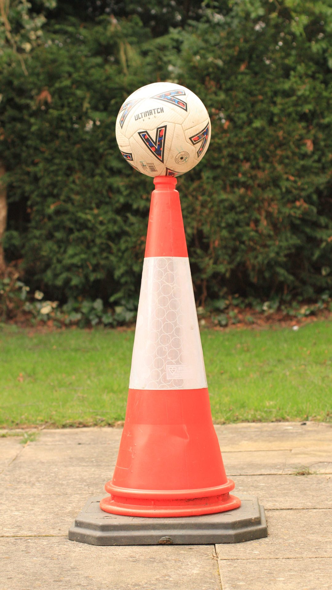 Football balanced on top of traffic cone