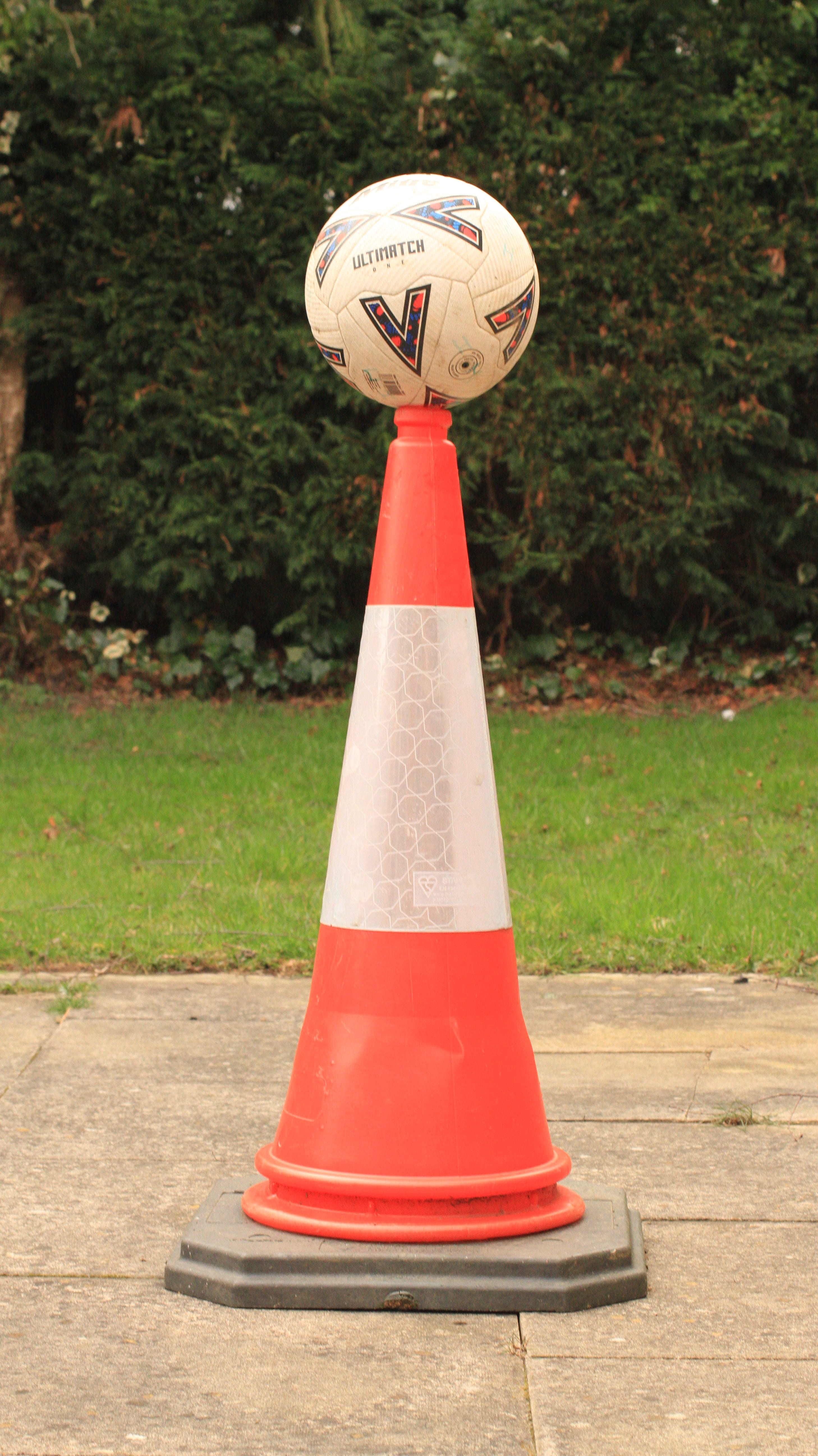 Football balanced on top of traffic cone