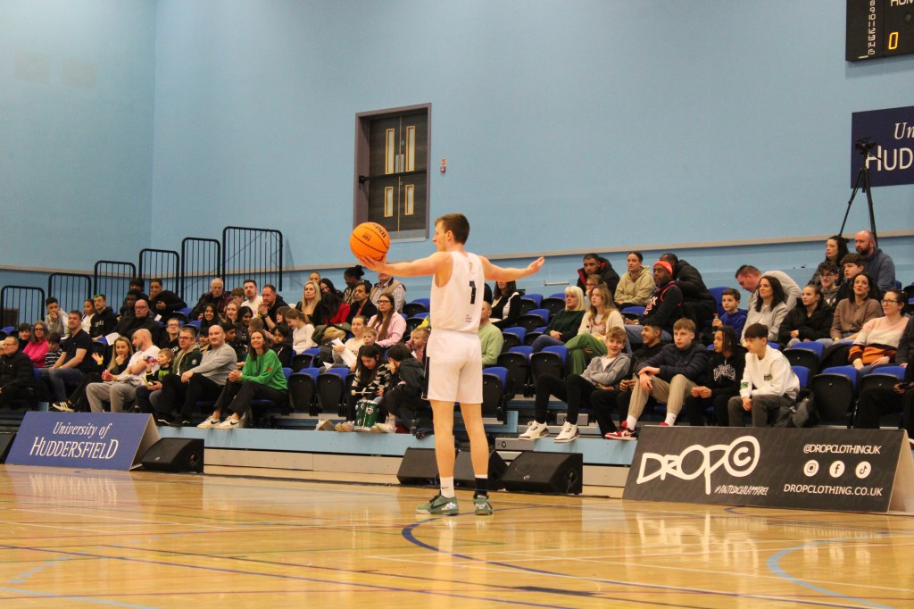 Basketball player with arms spread in T-position holding ball in one hand