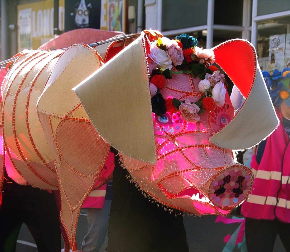 A giant pig puppet covered in flowers
