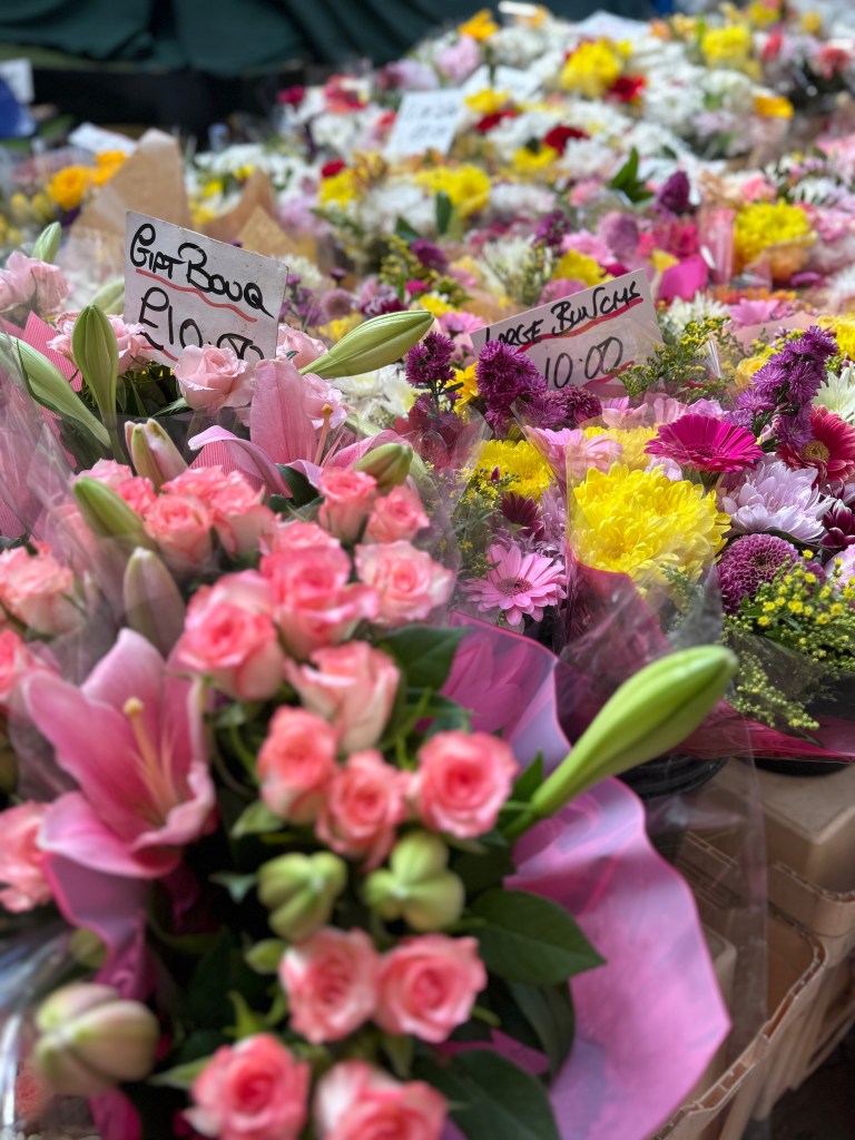 A blurred background of pink flowers in Kirkgate Market, with the focus on the vibrant petals in the foreground