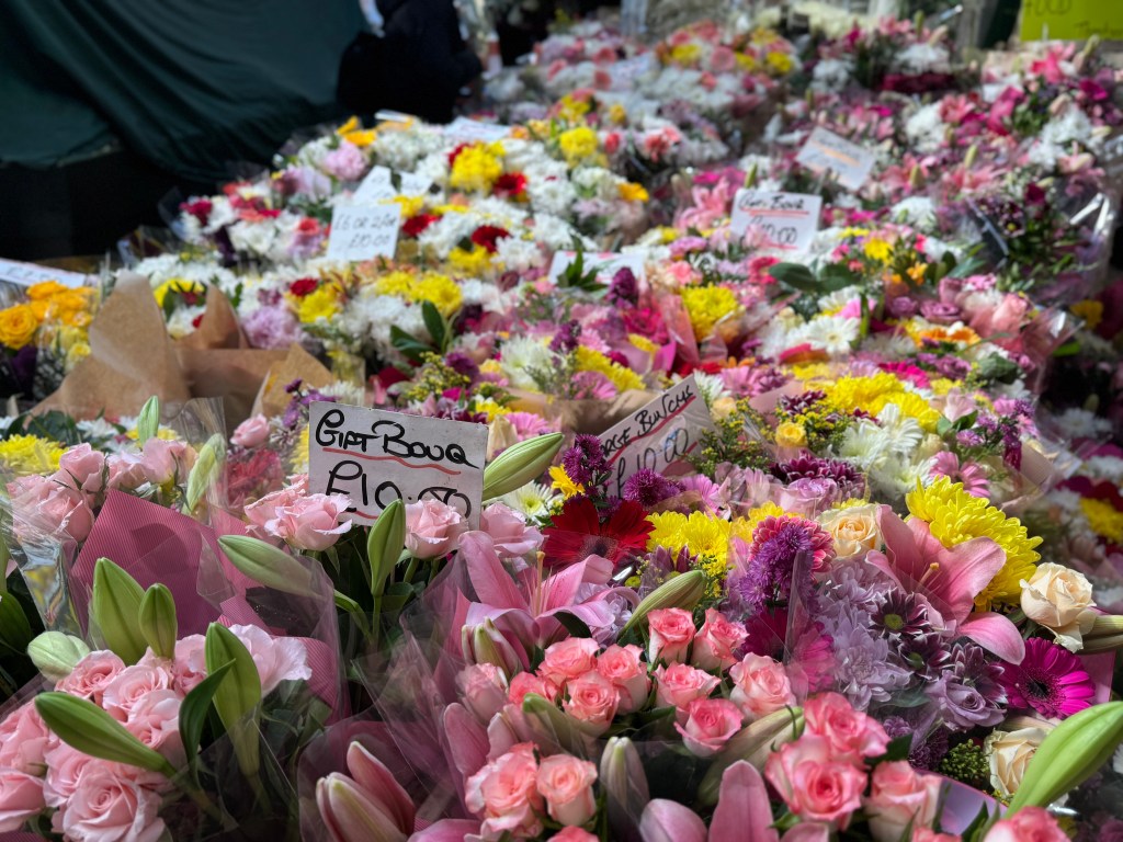 A blurred background of pink flowers in Kirkgate Market, with the focus on the vibrant petals in the foreground