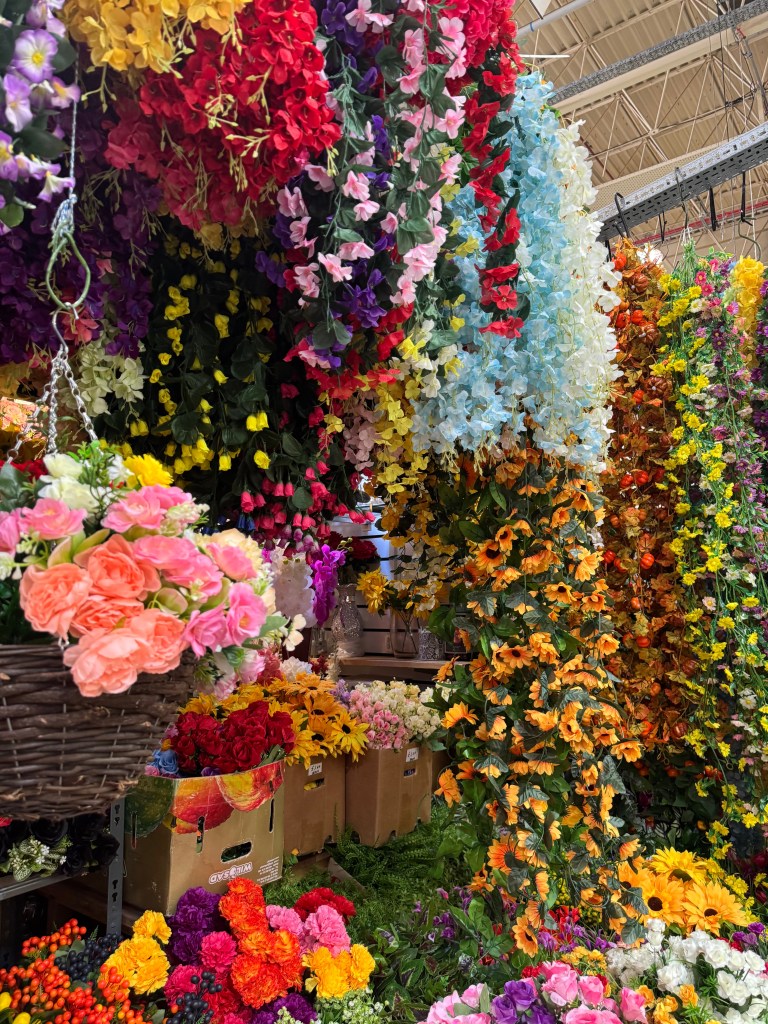 A display of coloruful artificial flowers hanging in a variety of bright hues at Kirkgate Market