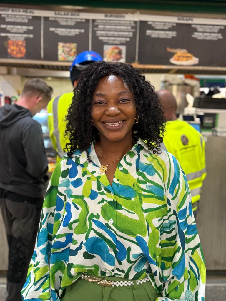 Jennifer Barry stands outside Jenny’s Jerk Chicken in Kirkgate Market, smiling at the camera