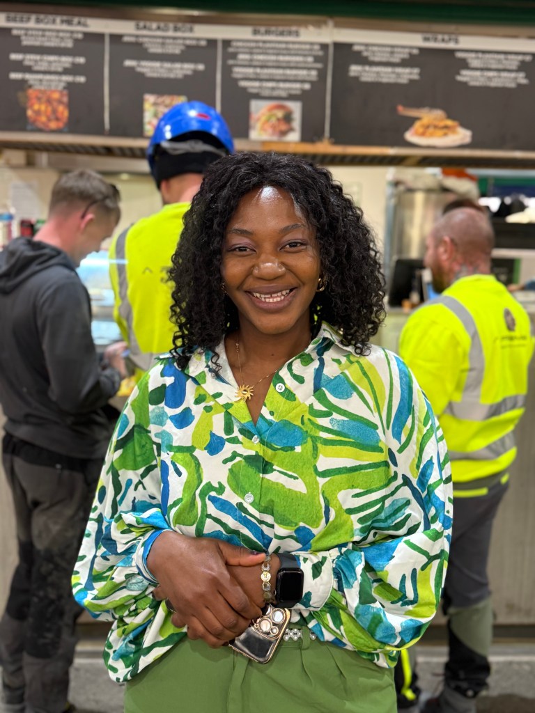 Jennifer Barry stands outside Jenny’s Jerk Chicken in Kirkgate Market, smiling at the camera
