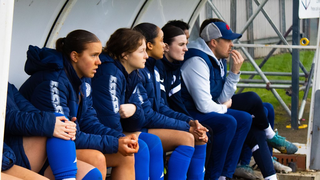 Rob Mitchell and the substitutes sat on the bench looking on towards the match that is out of frame