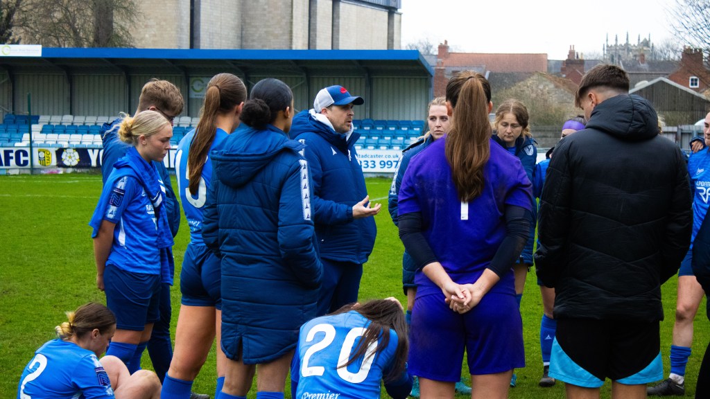 Rob Mitchell surrounded by a circle of Halifax players who look disappointed as he gives his team talk on the pitch